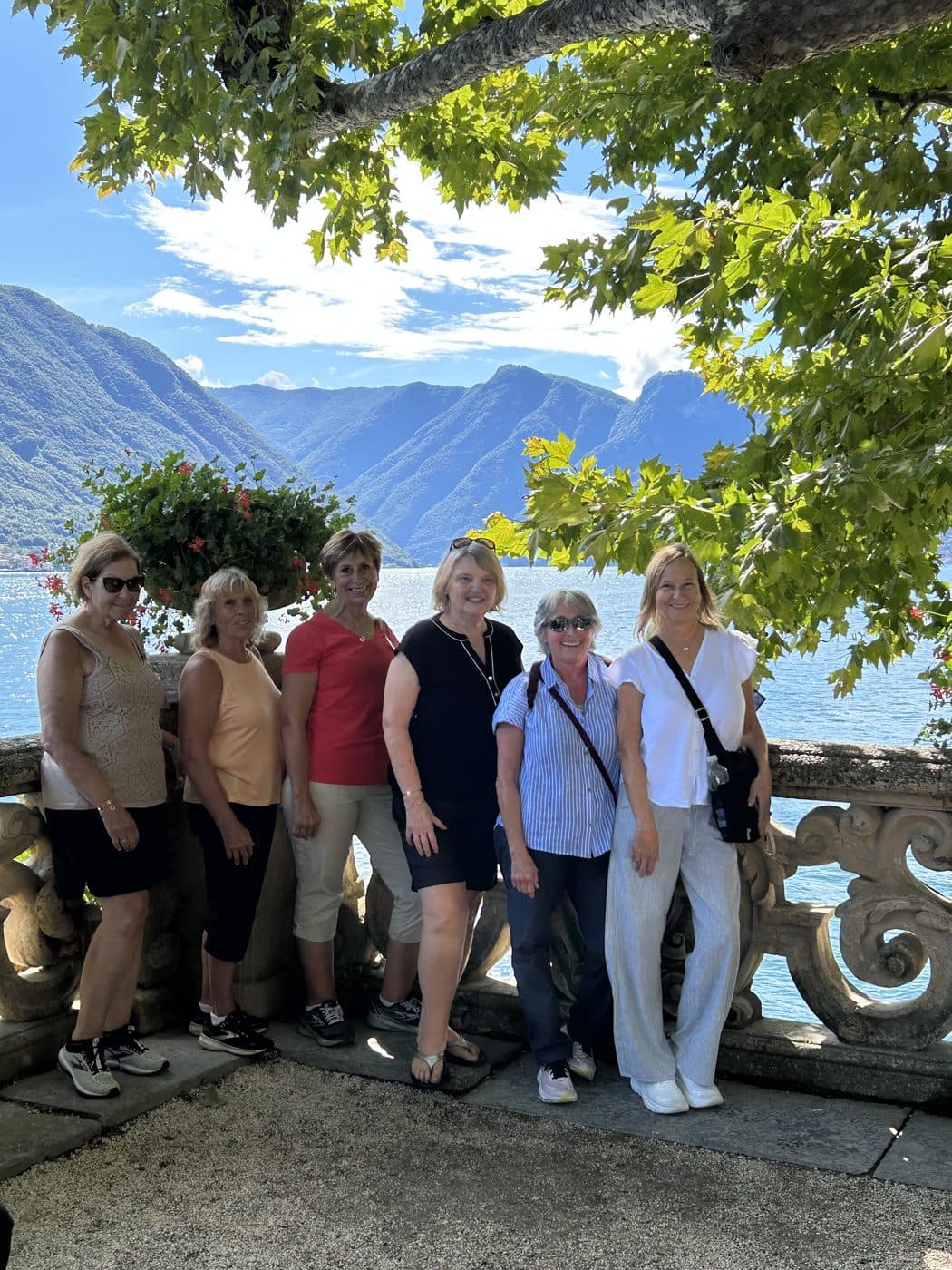 Six Tom's Christian Tours travelers smiling together on a terrace above a mountain lake
